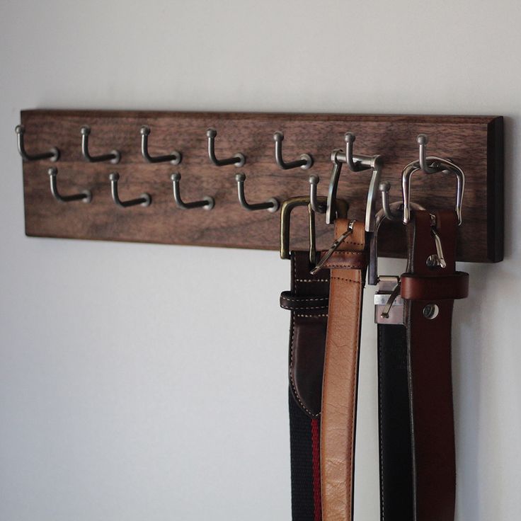 several belts are hanging on a wall with metal hooks and leather straps attached to them