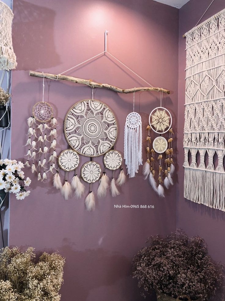 there is a wall hanging with dream catchers on it and flowers in the vase