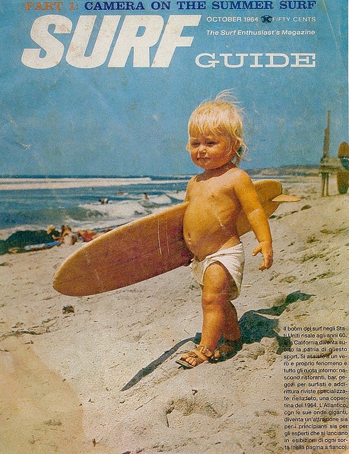 a young child carrying a surfboard on the beach