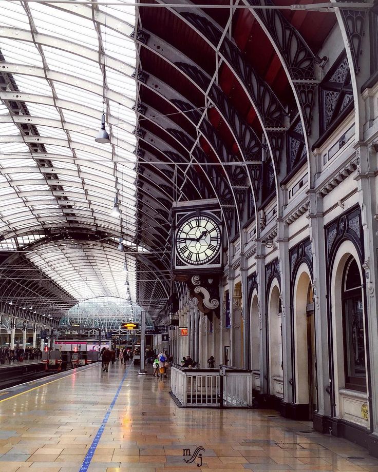 a clock is hanging from the ceiling in a train station