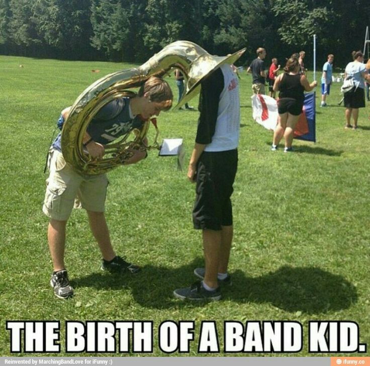 two men are standing in the grass and one has a snake on his head