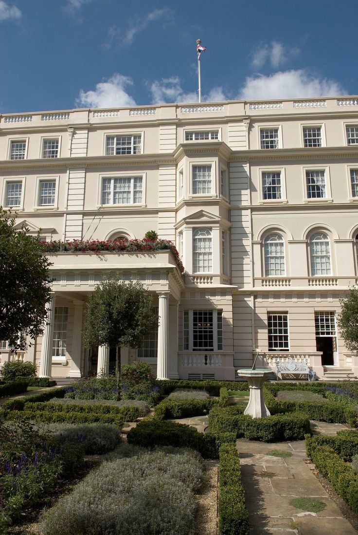 a large white building with many windows and bushes