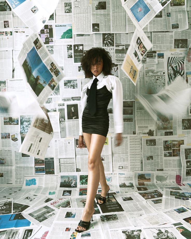 a woman standing in front of a pile of newspapers with her legs spread wide out