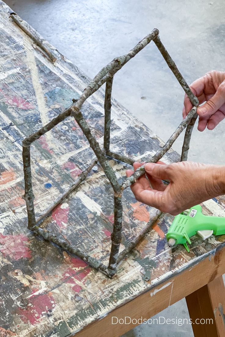 two hands are working on a piece of art that is being made out of wood