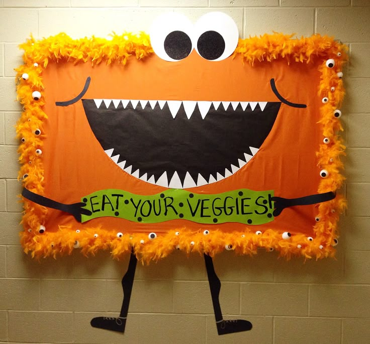 a bulletin board with an orange monster and words eat your veggies written on it