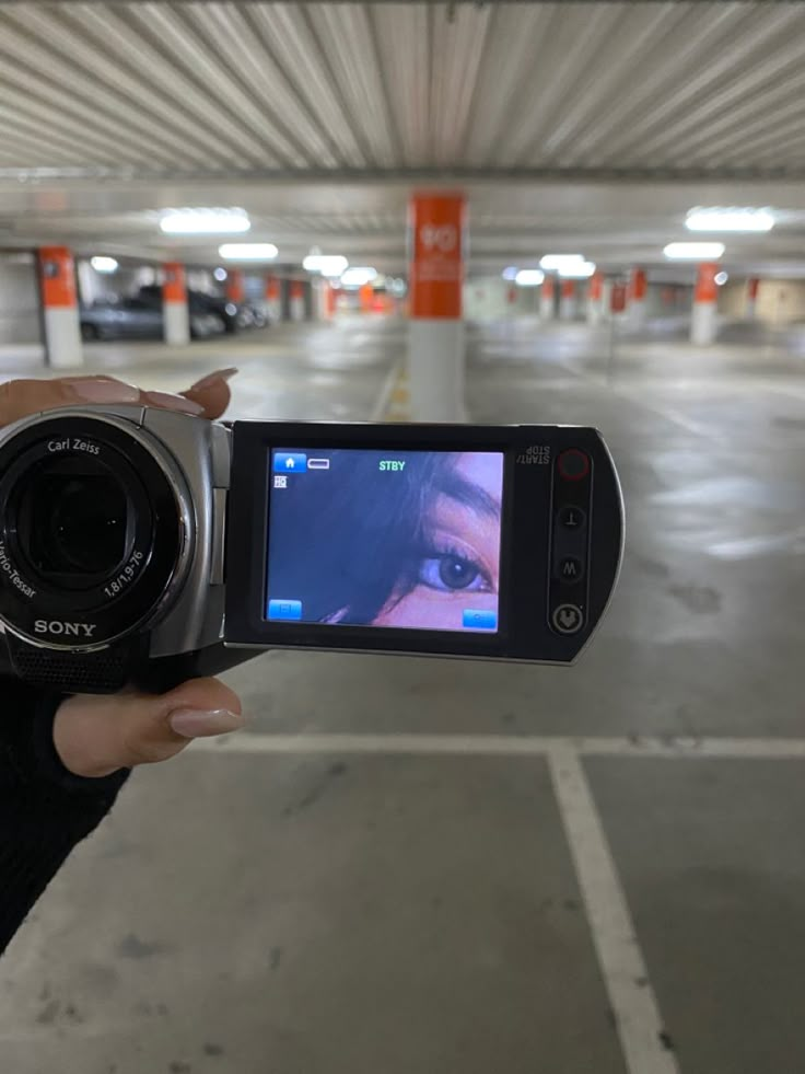 a person holding up a camera to take a picture in an empty parking garage area