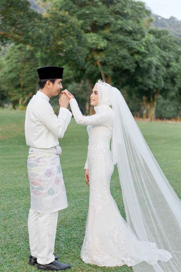 a bride and groom standing together in the grass