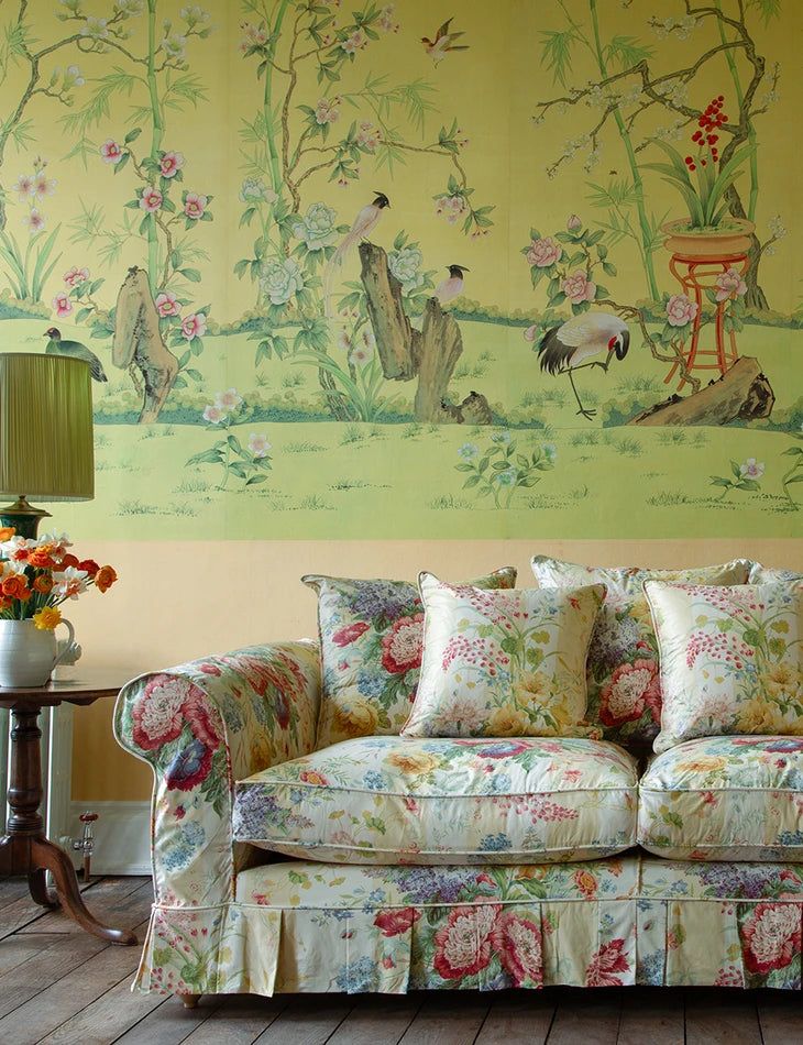 a couch sitting in front of a painting on the wall next to a table with flowers