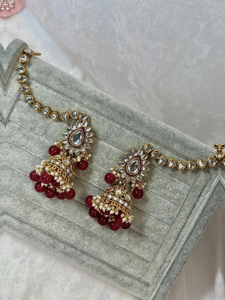 This faux kudan earrings comes with attached ear chains. Please note this doesn't include tikka.  Tikka is avialable to be purchased seperately please see tikka option to shop matching tikka. Approximately measures 3 inch length jhumka including bell x 7 inch length including chain x 1.5 inch wide. Chain measure 4 inch length  Ready to ship! Dangling Beads Jhumkas For Diwali, Dangle Jhumkas With Dangling Beads For Diwali, Diwali Dangle Jhumkas With Dangling Beads, Bollywood Style Dangling Beads Jhumkas For Party, Festive Chandelier Earrings With Latkans As Gift, Bollywood Style Jhumkas With Dangling Beads For Party, Bollywood Style Jhumkas With Dangling Beads, Red Bollywood Tikka With Latkans, Red Bollywood Style Tikka With Latkans