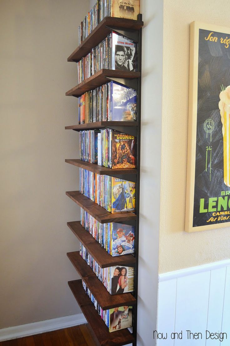 a book shelf filled with dvd's next to a wall mounted movie poster on the wall