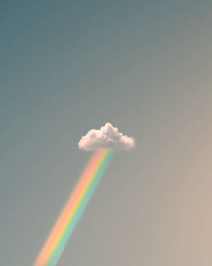 a rainbow in the sky with a cloud above it