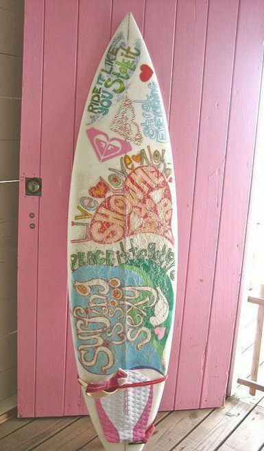 a white surfboard sitting on top of a wooden floor next to a pink wall