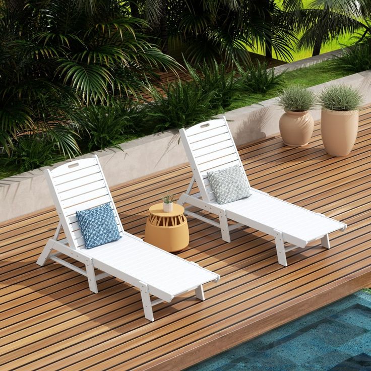 two white lawn chairs sitting on top of a wooden deck next to a swimming pool