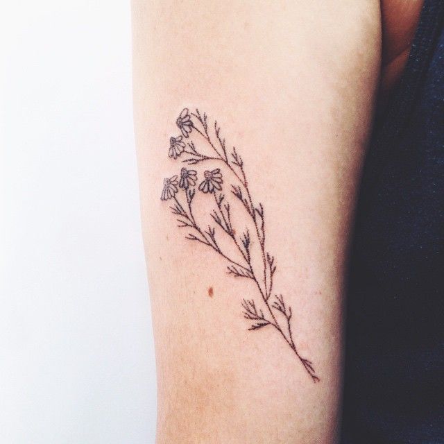 a woman's arm with a small flower tattoo on the left side of her arm