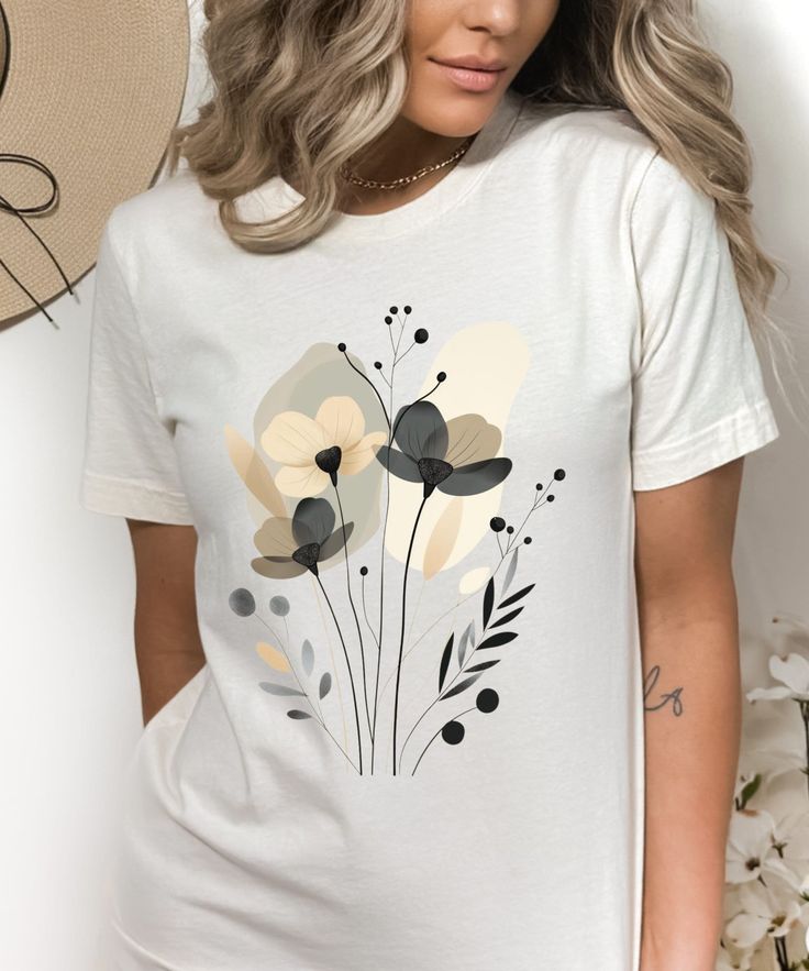 Introducing the exquisite "Boho Wildflowers T-Shirt" - a true celebration of floral beauty and artistic expression, perfect for the garden lover or botanical enthusiast. This shirt features a stunning design inspired by both Art Nouveau and Art Deco styles, blending elegant pastel floral patterns with vintage botanical prints. The soft, neutral background accentuates the gentle beauty of black and beige wildflowers, creating a piece that is both timeless and contemporary. Crafted with lovers of Floral T-shirt Design, White Digital Print Top For Summer, White Botanical Style Shirt With Floral Print, White Digital Print Top For Spring, Bohemian Short Sleeve Tops With Custom Print, Artistic Crew Neck Shirt For Summer, Botanical Short Sleeve Graphic Shirt, Summer Short Sleeve T-shirt With Digital Print, Bohemian Shirt With Floral Print And Crew Neck