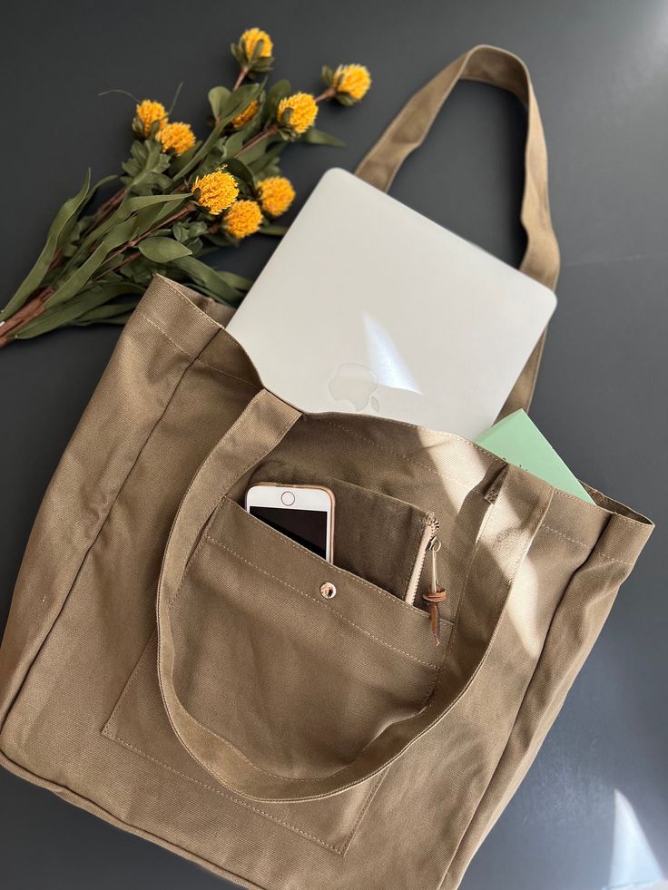 "This brown neutral tone colored tote fits everything you need for the day, on the run to school, to work, to grocery shopping, and even a relaxing weekend at a coffee shop, it got you covered. This cream tote is designed to fit MacBook pro and air, your daily journal, textbooks, and makeup pouches. This tote is designed with a large exterior pockets with a magnet button to keep your phone safe but easy access to it, and an interior pocket for your wallet. Extra seams on both sides of the bag ar Khaki Canvas Tote Bag With Pockets, Khaki Canvas Tote Bag With Canvas Lining, Khaki Canvas Tote Bag For Daily Use, Khaki Tote Canvas Bag For Daily Use, Casual Laptop Bag With Large Capacity And Double Handle, Khaki Canvas Tote Bag, Casual Brown Tote Laptop Bag, Casual Large Capacity Double Handle Laptop Bag, Khaki Cotton Shoulder Bag For Daily Use