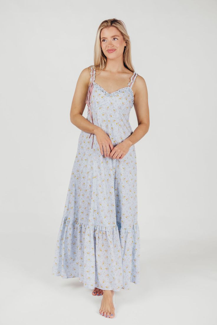 Simple but absolutely charming, the Penelope Maxi Dress is just the ticket for your next summer event. From its delicate ruffled details to its in-seam pockets and flounced skirt, the Penelope is all cottagecore elegance. Dressed up with heels or dressed down with slides or mules, this dress promises season after season of beautiful wear. Available in two colorways. FIT: Runs true to size. MATERIAL: Cotton. GARMENT DETAILS: Lightweight floral maxi dress with V-neckline, ruffled double straps, and a cinched waist. Features full skirt with ruffled hem, dual in-seam pockets, and a smocked back panel. SIZE GUIDE: XS (0-2) / S (2-4) / M (6-8) / L (10-12) / XL (14-16) MODEL DETAILS: MISSES Mackenzie - Size S Heather - Size S Bust 34" 34" Waist 27.5" 27.5" Hips 40.5" 37.5" Height 5'7" 5'7" Spring Garden Party Ruffle Dress With Ruffled Straps, Spring Sundress With Ruffled Straps For Picnic, Spring Tiered Lined Maxi Dress, Spring Daywear Ruffle Dress, Summer Light Blue Dress With Ruffled Straps, Summer Light Blue Dresses With Ruffled Straps, Blue Cotton Ruffle Dress For Summer, Spring Ruffle Dress For Garden Party With Smocked Bodice, Spring Dresses With Ruffled Straps For Daywear