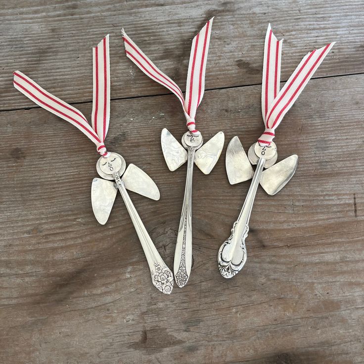 three silver spoons with red and white ribbons on them