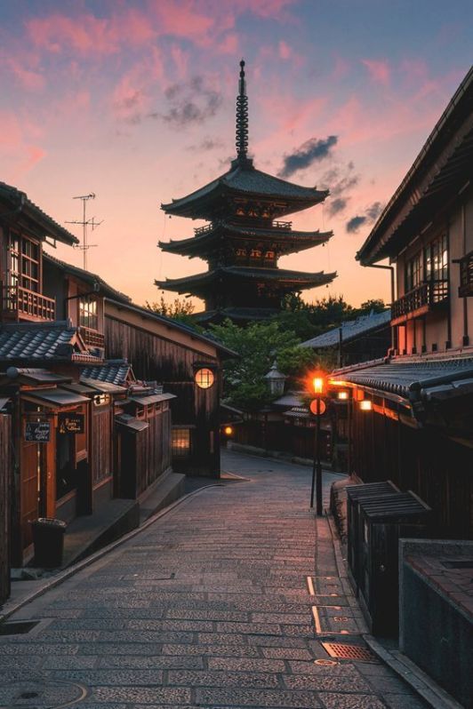 an alley way with buildings and lanterns lit up at dusk