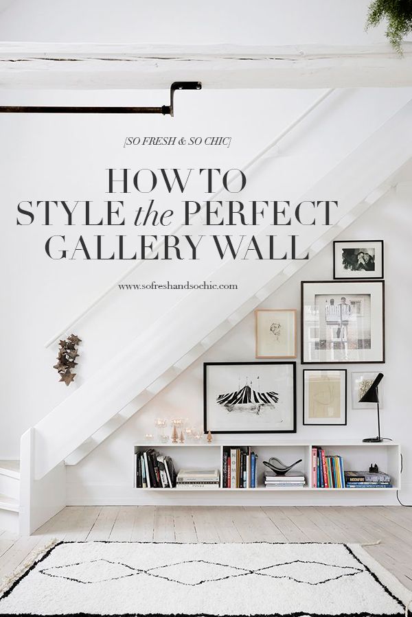 a white room with bookshelves and pictures on the wall, below a slanted stair case