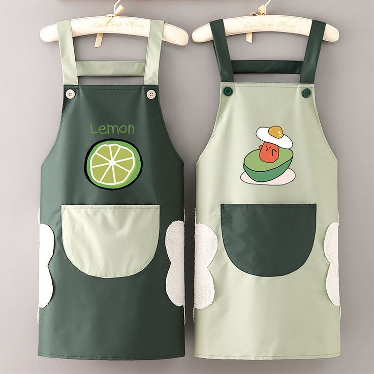 two children's aprons with lemon and lime designs on them hanging from hooks