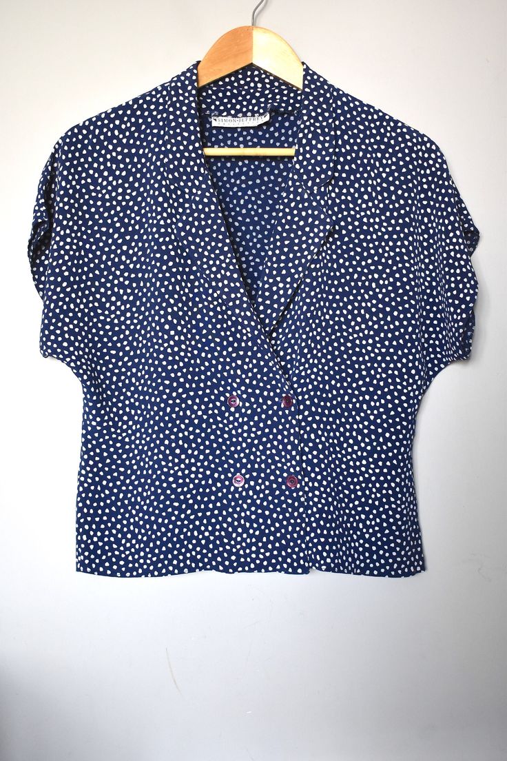 "Vintage 90's print polka-dot double-breasted cropped blazer shirt with a lapeled deep V-neck and cap sleeves. Slightly fitted at the high waist. Fits relaxed. That's one cool summer top with various styling options. Made in England. Brand: Simon Jeffrey Material: 100% viscose Size: tagged size 16UK/14US/42EUR. For a best fit, please refer to the measurements below. Appr. Measurements (taken with shirt lying flat, please double armpit to armpit, waist and bottom hem): armpit to armpit: 21\"/53,5 Vintage Relaxed Fit Cropped Tops, Vintage Cropped Tops With Relaxed Fit, Retro V-neck Top For Workwear, Cropped Summer Shirt With Button Closure, Summer Cropped Shirt With Button Closure, Trendy Polka Dot Short Sleeve Tops, Trendy Short Sleeve Tops With Polka Dot Pattern, Collared Cotton Polka Dot Tops, Polka Dot Collared Cotton Top