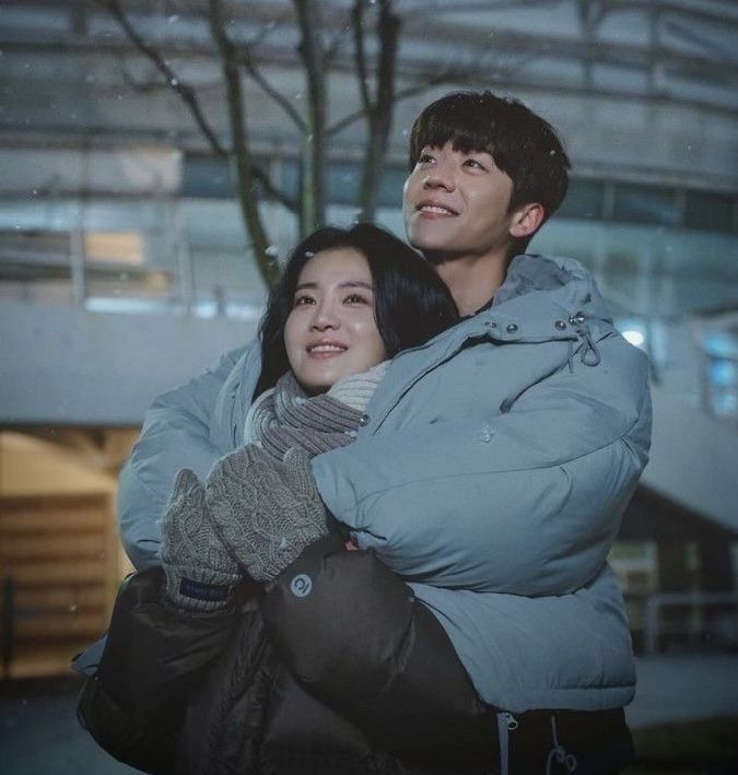 a man and woman standing next to each other in front of a building at night