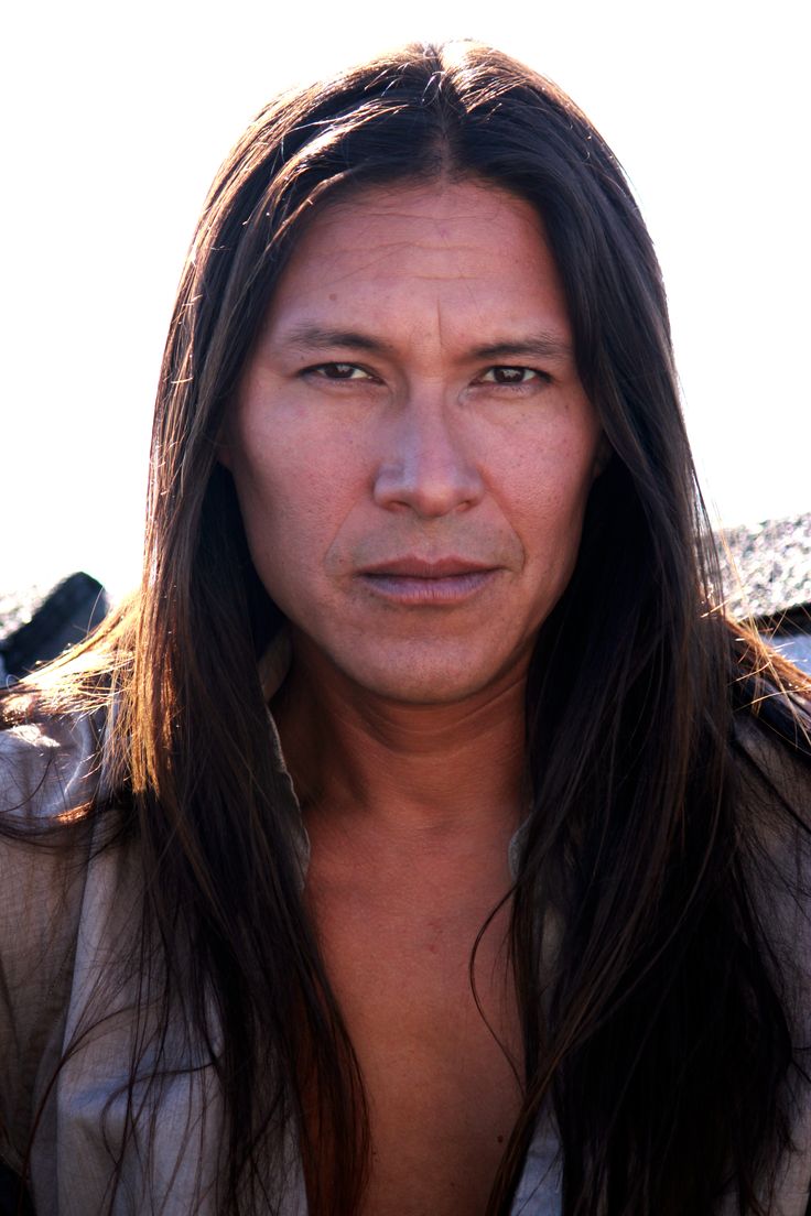 a man with long hair and no shirt is looking at the camera while wearing a jacket