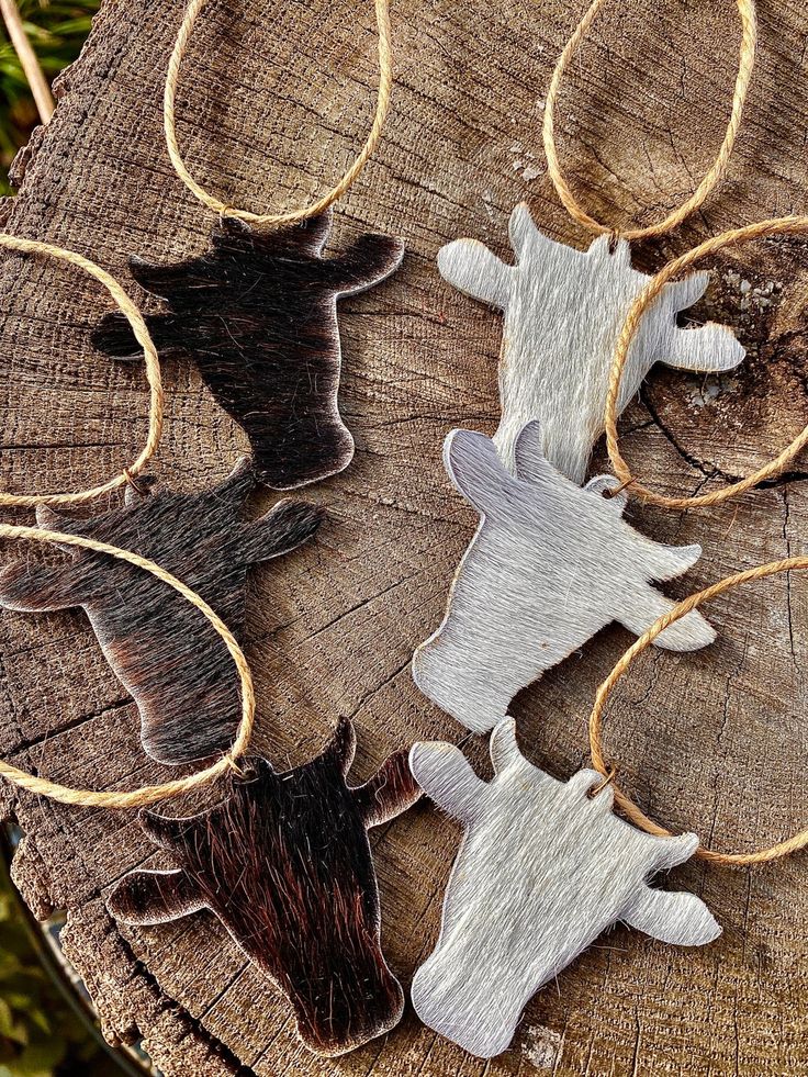 three metal cow ornaments sitting on top of a tree stump