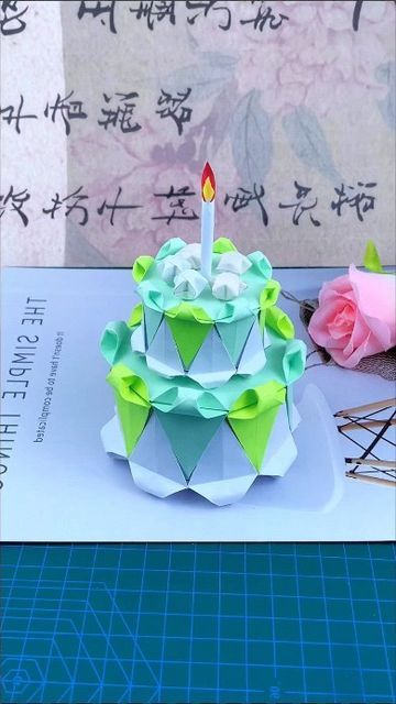 a birthday cake sitting on top of a table next to a pink rose and another piece of paper