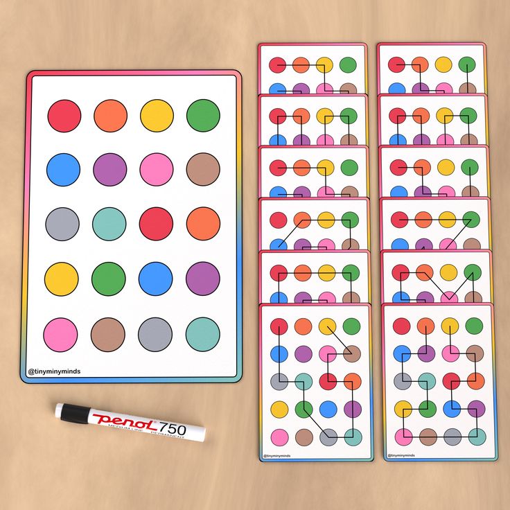 two sheets of colored dots next to a marker and pen on a wooden table with markers