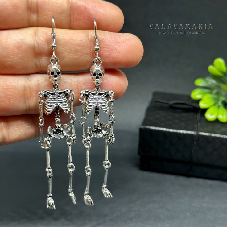 Get ready to dance the night away with these one-sided skeleton earrings in a vintage metallic silver finish! Perfect for any occasion - Halloween, Day of the Dead, a birthday party, or a night out with friends. Lightweight, articulated (all limbs are movable) and beautifully detailed, these earrings make a unique and original gift for yourself or someone special. Add some gothic, punk, and tattoo fashion to your look with these playful and quirky CALACAMANIA™ accessories Earrings details: Size: Edgy Skull Earrings For Parties, Bone Colored Metal Earrings For Pierced Ears, Punk Skull Earrings For Party, Edgy Halloween Jewelry For Costume Party, Punk Style Hand Cast Halloween Jewelry, Metal Halloween Party Jewelry, Gothic Skull Earrings For Party, Punk Style Single Earring For Halloween, Halloween Punk Style Single Earring