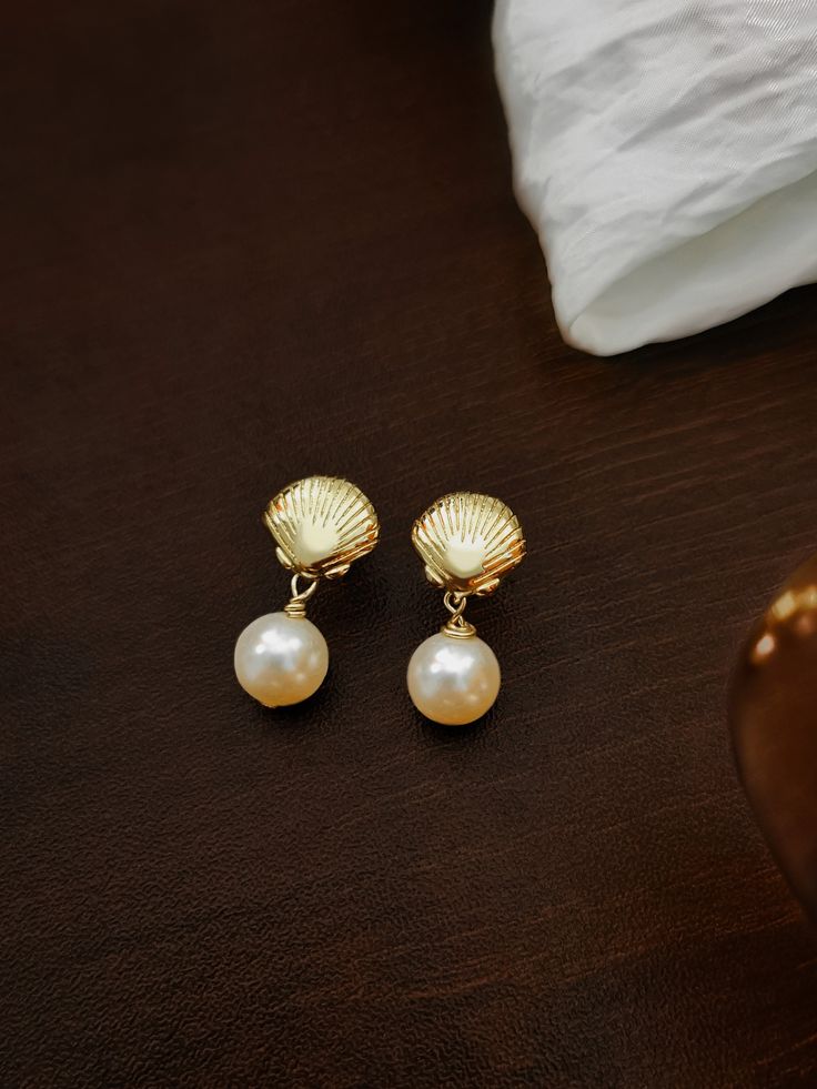 This pair of pearl drop earrings are made of high quality Swarovski pearls in 14k gold plated. The seashell shape is inspired by our fond childhood memory of picking up seashells at the beach. Hope they will remind you of your happy memories as well!   They are perfect for your daily outfit. An elegant yet fun piece to boost up your mood even on the gloomiest day.  ✨ SHIPPING INFORMATION * 3-5 days processing time for all orders   * CANADA: - Free shipping DOES NOT include tracking. Shipped with Elegant Shell With Pearl Charm, Shell-shaped Pearl Charm Earrings As Gift, Shell-shaped Pearl Earrings With Pearl Charm, Elegant Gold Shell With Pearl Charm, Shell-shaped Pearl Earrings For Gift, Shell-shaped Pearl Drop Earrings For Gifts, Gold Dangle Shell Earrings, Pearl Shell Drop Earrings With Pearl Drop Detail, Gold Plated Teardrop Pearl Earrings For Gift