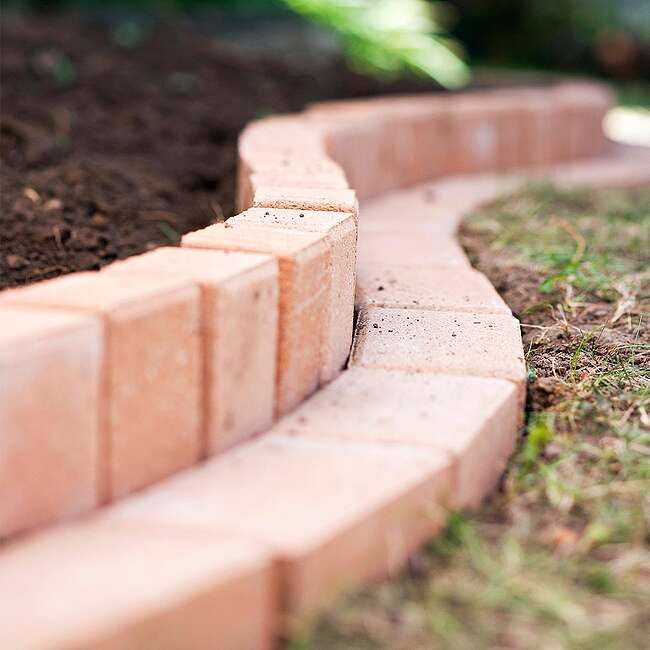 a close up of a brick walkway in the grass with dirt on the ground next to it