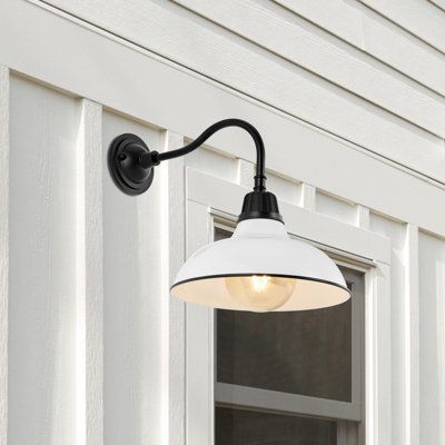 an outdoor light is mounted on the side of a house with white siding and windows