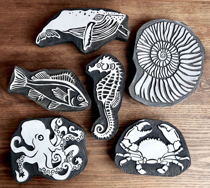 four different sea creatures painted on rocks sitting on top of a wooden table next to each other