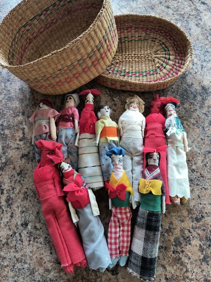 many dolls are sitting next to each other on the floor in front of a basket