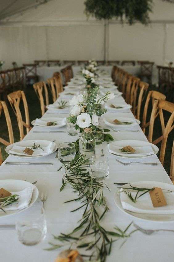 a long table is set with white plates and place settings for the guests to eat