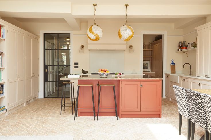 a kitchen with two pendant lights hanging from the ceiling and an island in the middle