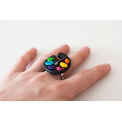 a person's hand holding a black ring with multicolored buttons