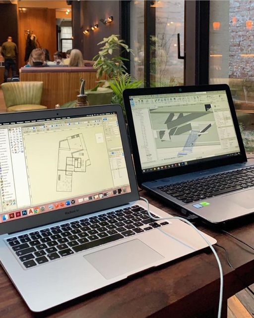 two open laptops sitting on top of a wooden table