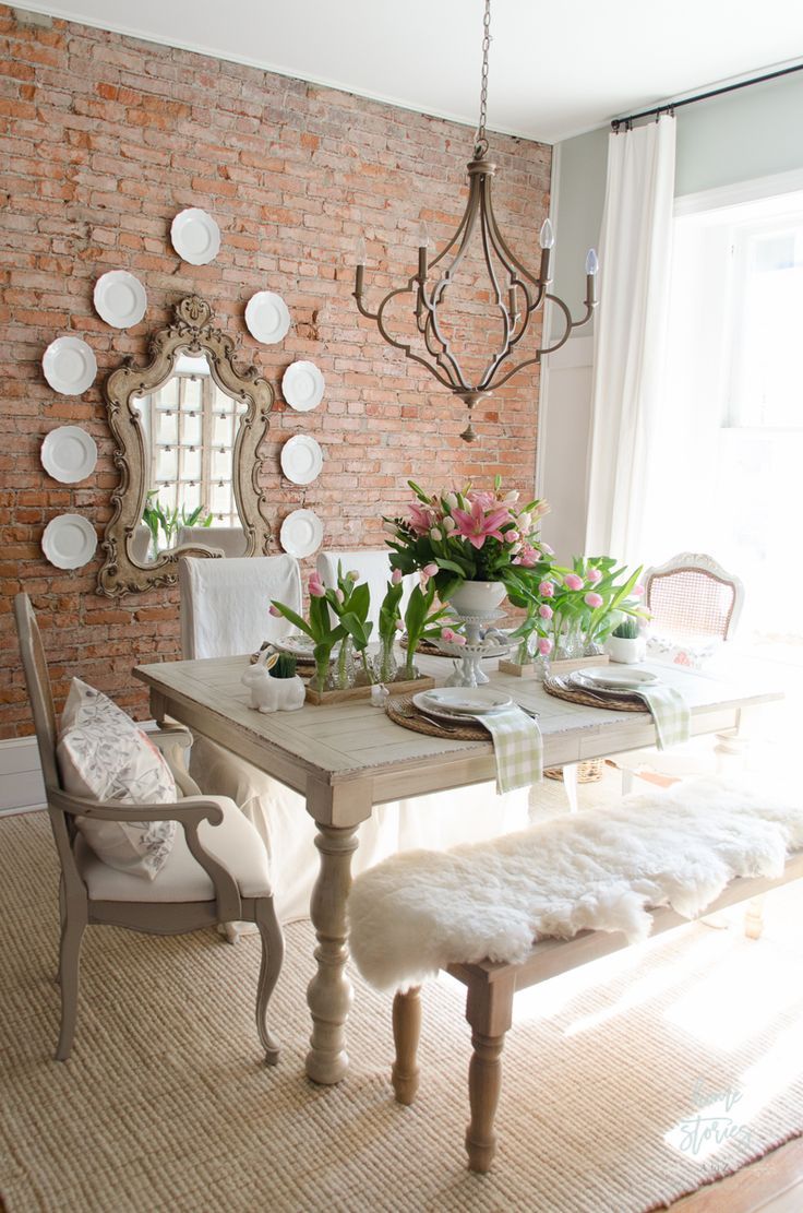 a dining room table with plates on the wall and flowers in vases at the end