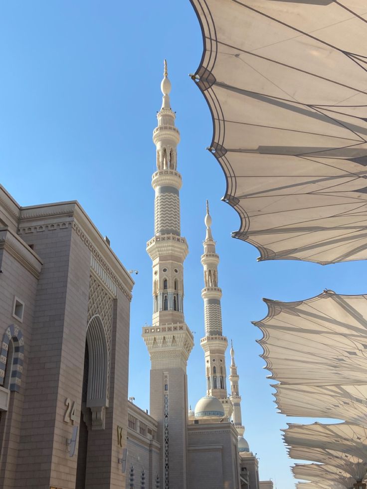 a large white building with a clock tower next to it's roof and some umbrellas