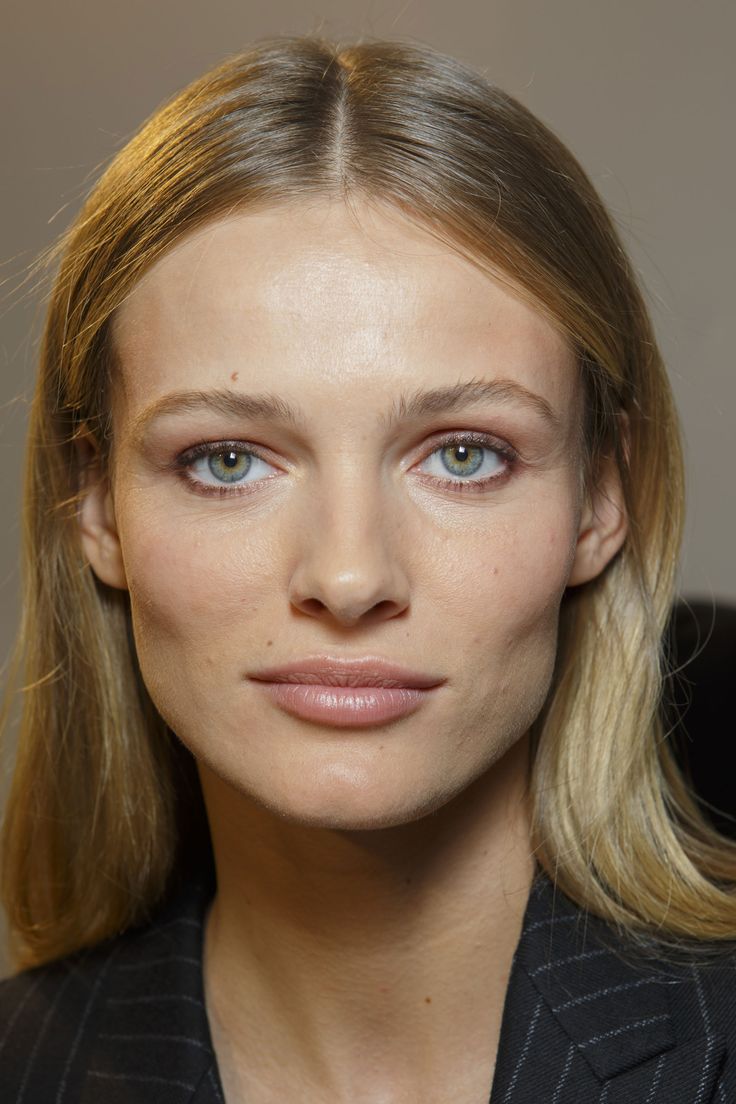 a woman with blonde hair and blue eyes is posing for the camera, wearing a black suit