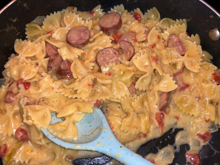 a skillet filled with pasta and sausages on top of it's side