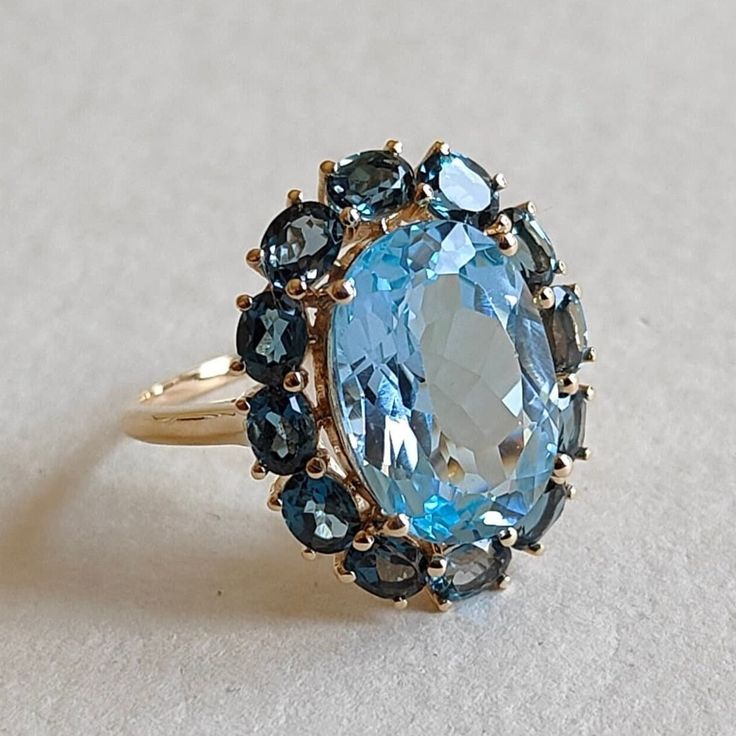 This stunning ring is set in 14k Solid Yellow Gold with Natural Sky Blue Topaz and London Blue Topaz with utmost precision. It is an unique statement gemstone ring for nearly every occasion and is completely hassle-free jewelry.  ITEM DETAILS: * CENTER GEM: Sky Blue topaz * GEM SIZE: 10X14mm * GEM SHAPE: Oval * SIDE GEM: London Blue topaz * GEM SIZE: 4x3mm (12 pcs) * GEM SHAPE: Oval * Total Gem weight: 9.85 carats * Gold Purity: 14KT (58.33% approx.) * Gold Weight: 3.09 gram  * Total Weight of t Blue Oval Multi-stone Cluster Ring, Blue Multi-stone Sapphire Ring In 14k Gold, Anniversary Blue Topaz Cluster Ring, Luxury Blue Topaz Multi-stone Ring, Blue Gemstone Cluster Ring Fine Jewelry, Blue Topaz Multi-stone Ring In 14k Gold, Blue Multi-stone Topaz Ring For Wedding, Blue Oval Topaz Ring In 14k Gold, Oval Blue Topaz Ring In 14k Gold