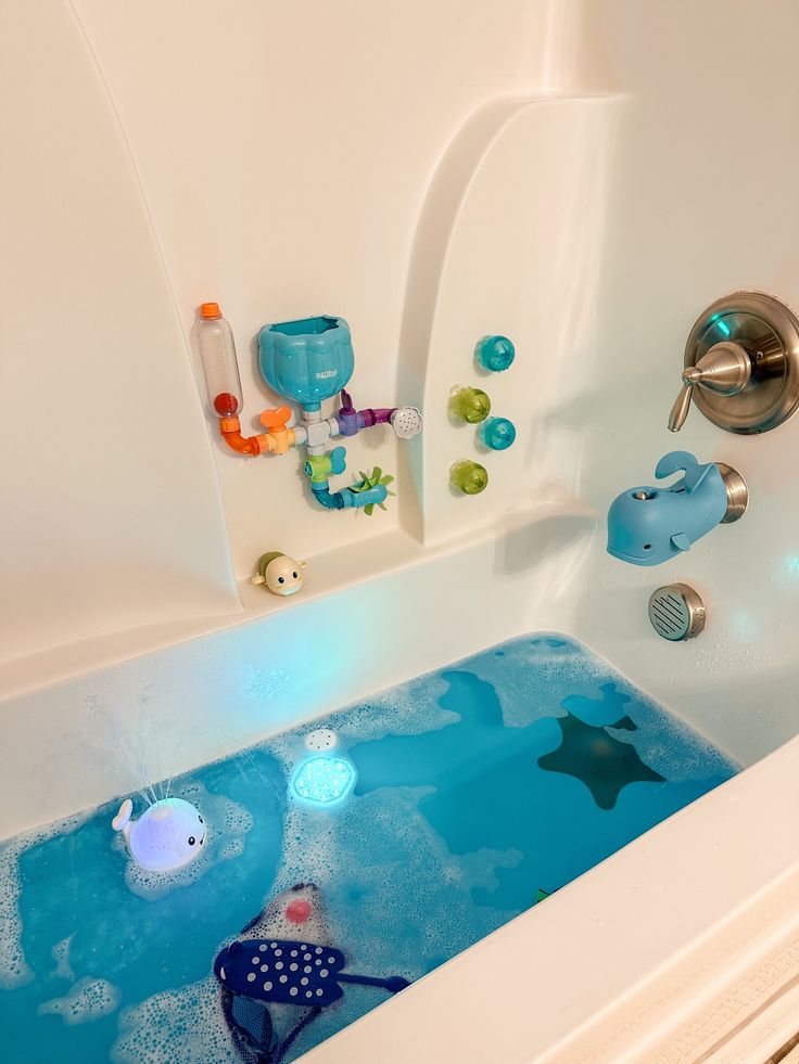 a bathtub with blue water and toys in it