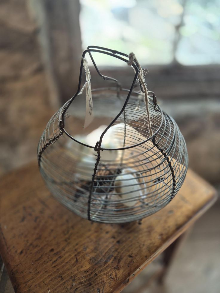 an old wire basket sitting on top of a wooden table