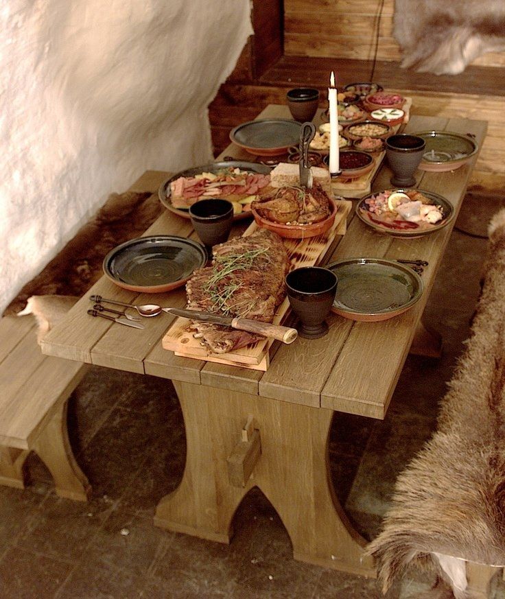 a wooden table topped with lots of plates and bowls filled with food next to a wall