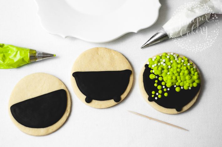 three decorated cookies sitting on top of a table next to a pen and paper plate